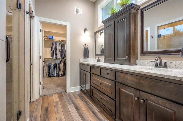 bathroom featuring double vanity, wood finished floors, a sink, and visible vents