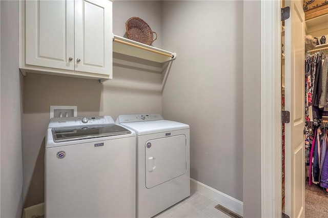 laundry room with light tile patterned floors, cabinet space, visible vents, washing machine and dryer, and baseboards