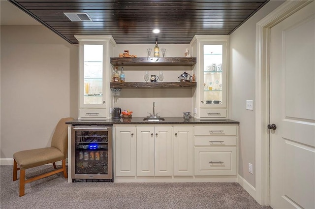 bar with light carpet, beverage cooler, visible vents, indoor wet bar, and a sink