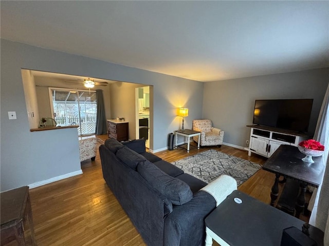 living room featuring ceiling fan, baseboards, and wood finished floors