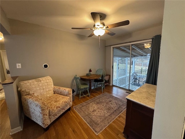 sitting room with ceiling fan and dark wood-type flooring