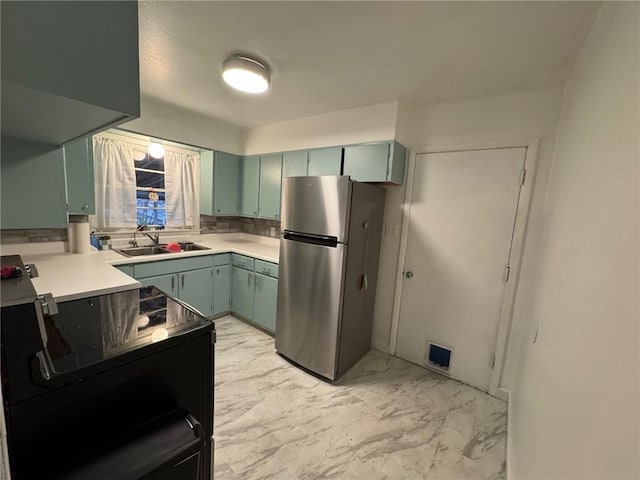 kitchen with electric range, a sink, marble finish floor, light countertops, and freestanding refrigerator