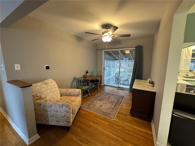 sitting room with ceiling fan, baseboards, and wood finished floors