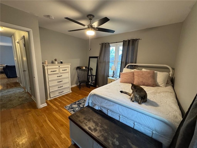 bedroom featuring ceiling fan, baseboards, and wood finished floors