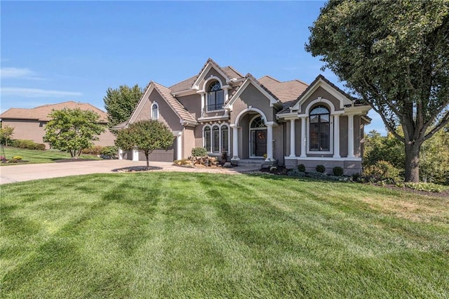 view of front facade with an attached garage, driveway, a front lawn, and stucco siding