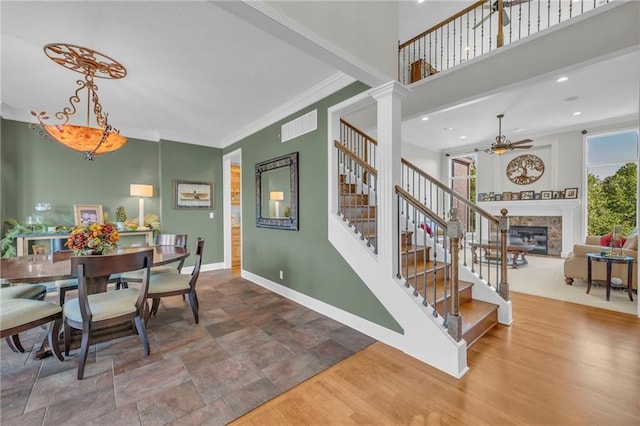 dining room featuring crown molding, visible vents, a high end fireplace, baseboards, and stairs