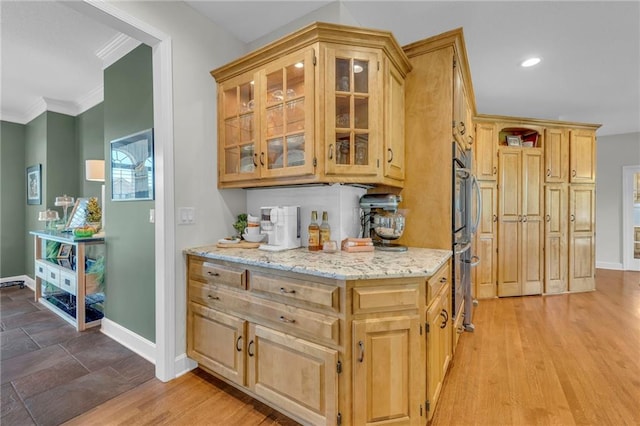 kitchen featuring baseboards, ornamental molding, light brown cabinets, and light stone countertops