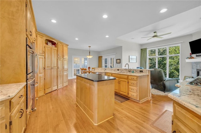 kitchen featuring light wood-style floors, a kitchen island with sink, a sink, and light brown cabinetry