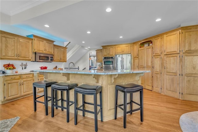 kitchen featuring stainless steel appliances, recessed lighting, light wood-style flooring, and a breakfast bar area