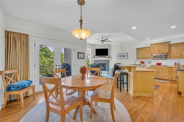 dining room featuring recessed lighting, a fireplace, a ceiling fan, french doors, and light wood-type flooring