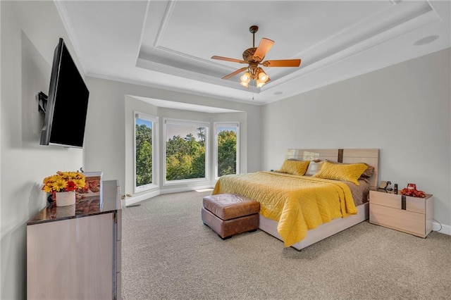 bedroom with ceiling fan, carpet floors, baseboards, a raised ceiling, and crown molding