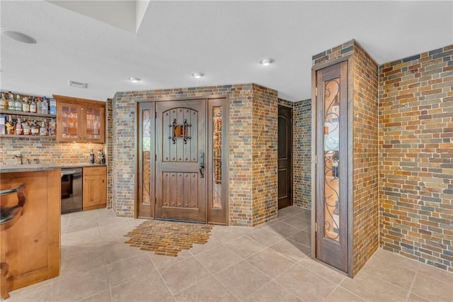 entrance foyer featuring light tile patterned floors, brick wall, wet bar, and visible vents