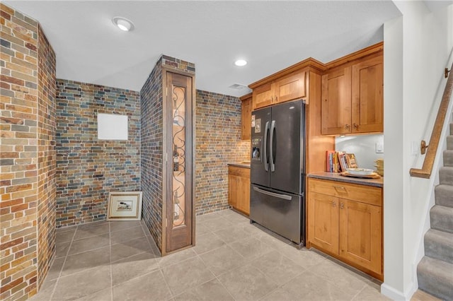 kitchen featuring light tile patterned floors, recessed lighting, tile walls, black refrigerator with ice dispenser, and brown cabinetry