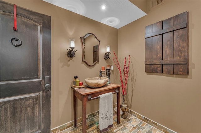 bathroom featuring brick floor, vanity, and baseboards