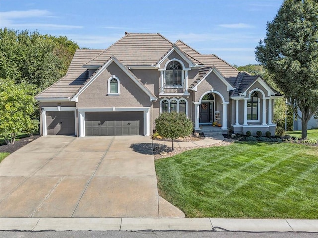 traditional-style house featuring a balcony, a tile roof, concrete driveway, stucco siding, and a front lawn