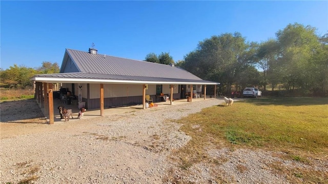 1147 Fern Rd, Fort Scott, KS 66701 - back of property with metal roof, a lawn, and a patio area