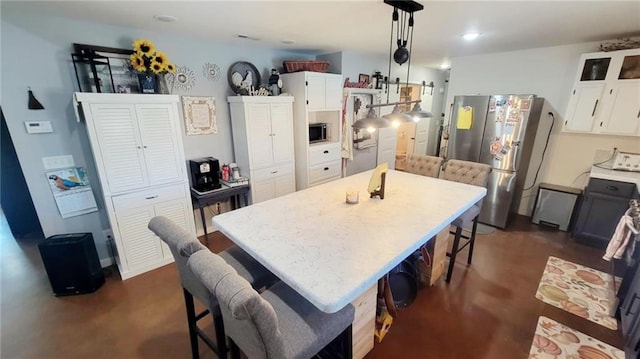 1147 Fern Rd, Fort Scott, KS 66701 - kitchen featuring appliances with stainless steel finishes, white cabinetry, a breakfast bar area, light countertops, and hanging light fixtures
