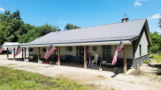 1147 Fern Rd, Fort Scott, KS 66701 - rear view of property featuring metal roof, covered porch, and a chimney