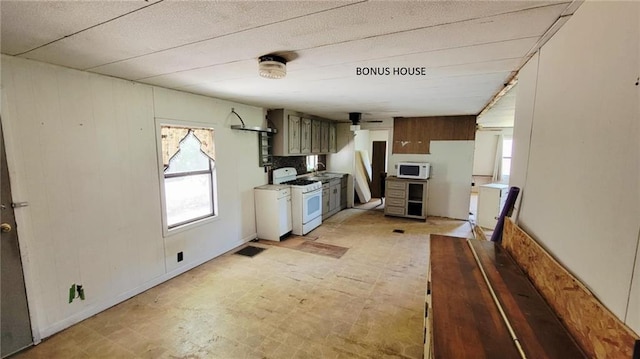 1147 Fern Rd, Fort Scott, KS 66701 - kitchen featuring white appliances, plenty of natural light, wooden walls, light floors, and ceiling fan