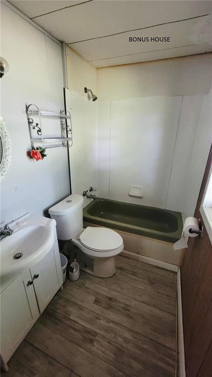 1147 Fern Rd, Fort Scott, KS 66701 - bathroom featuring vanity, wood finished floors, shower / tub combination, and toilet