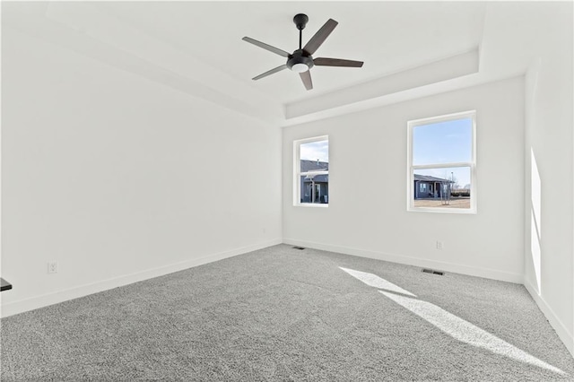 carpeted empty room with a raised ceiling and baseboards