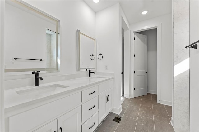 full bath with double vanity, tile patterned flooring, a sink, and baseboards