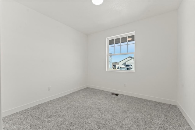 spare room featuring carpet floors, visible vents, and baseboards