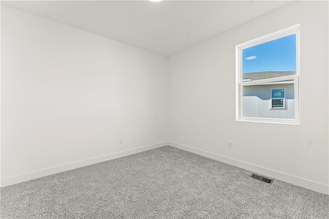 carpeted spare room featuring visible vents and baseboards