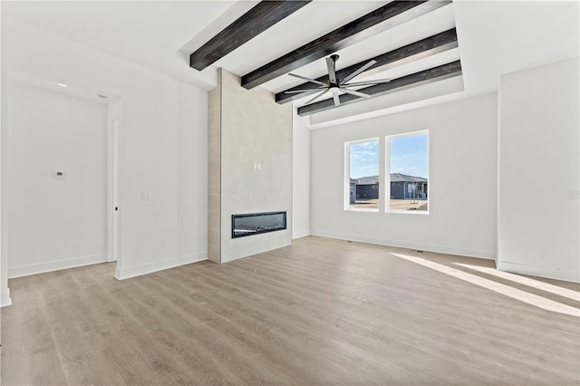 unfurnished living room featuring baseboards, a ceiling fan, beamed ceiling, light wood-type flooring, and a fireplace