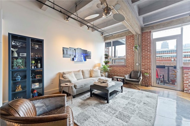 living room featuring rail lighting, brick wall, and baseboards