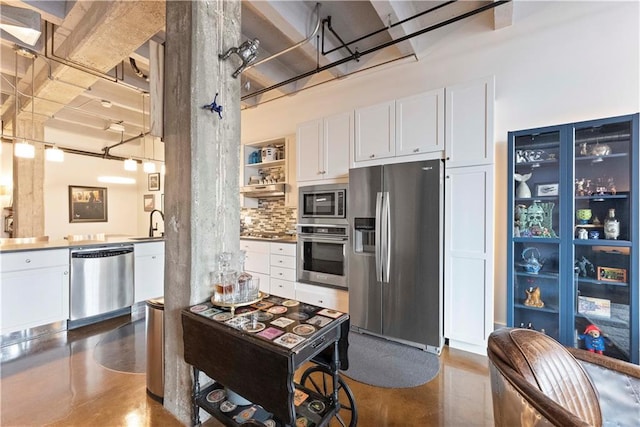 kitchen featuring tasteful backsplash, appliances with stainless steel finishes, concrete flooring, and white cabinets