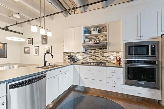 kitchen featuring stainless steel appliances, a sink, white cabinets, open shelves, and tasteful backsplash