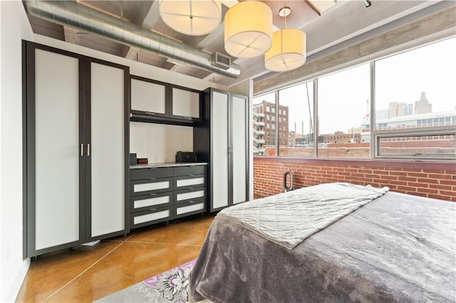 bedroom featuring brick wall, concrete floors, visible vents, and a city view