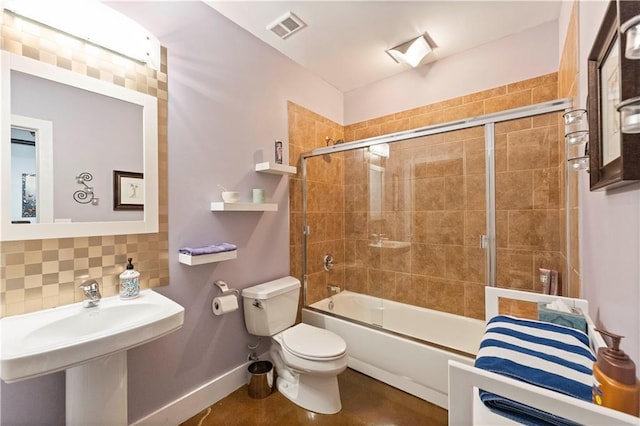 bathroom with baseboards, visible vents, decorative backsplash, toilet, and combined bath / shower with glass door