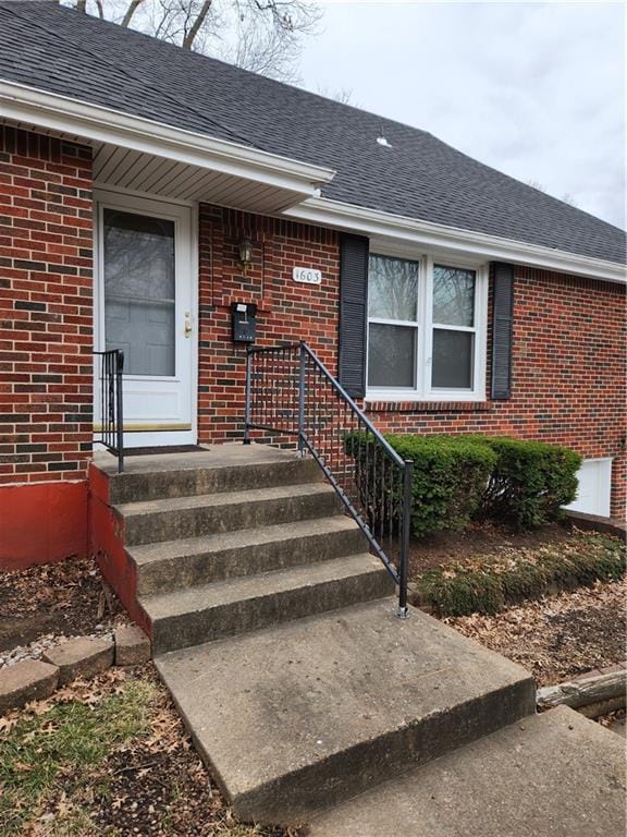 entrance to property with brick siding and roof with shingles