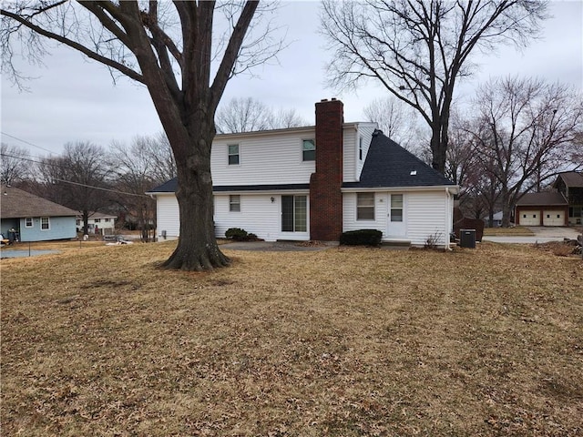 rear view of house featuring a lawn and a chimney