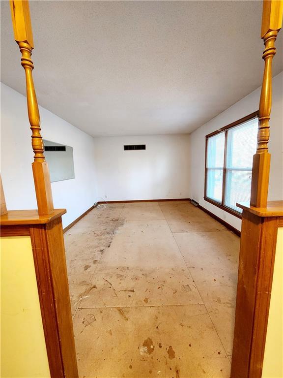 unfurnished room with visible vents, a textured ceiling, and baseboards