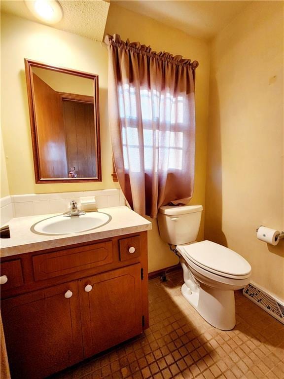 half bathroom with visible vents, toilet, vanity, and a textured ceiling