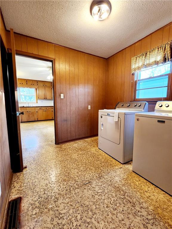 laundry area with washer and dryer, a textured ceiling, a wealth of natural light, and laundry area