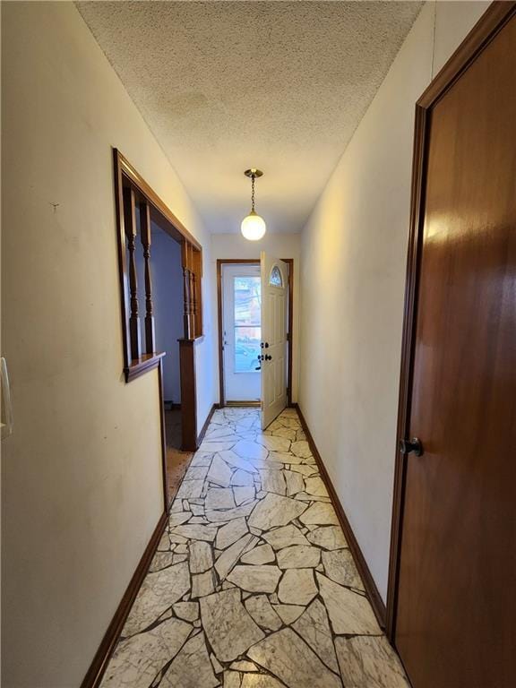 entryway with stone tile floors, a textured ceiling, and baseboards