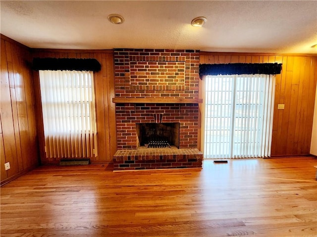 unfurnished living room with wood finished floors, wooden walls, and a fireplace