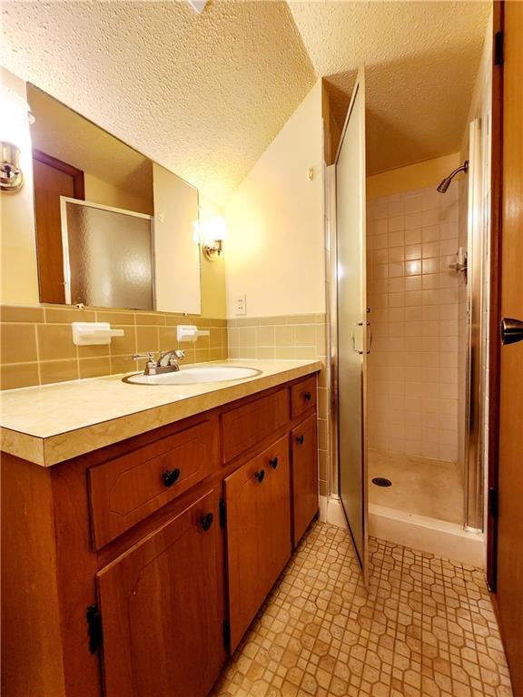 bathroom featuring vanity, a stall shower, and a textured ceiling