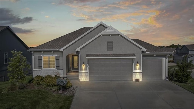 view of front of house featuring brick siding, driveway, an attached garage, and stucco siding