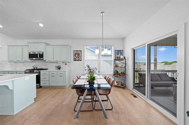 dining space with a chandelier, lofted ceiling, plenty of natural light, and light wood-style flooring