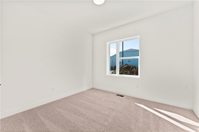 carpeted spare room with visible vents and baseboards