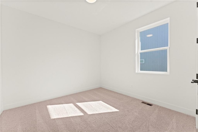 spare room with baseboards, visible vents, and light colored carpet