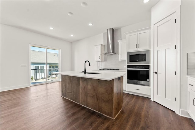 kitchen featuring dark wood-style flooring, stainless steel microwave, wall oven, a sink, and wall chimney range hood