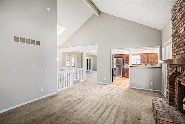 unfurnished living room with visible vents, light colored carpet, a fireplace, high vaulted ceiling, and beam ceiling