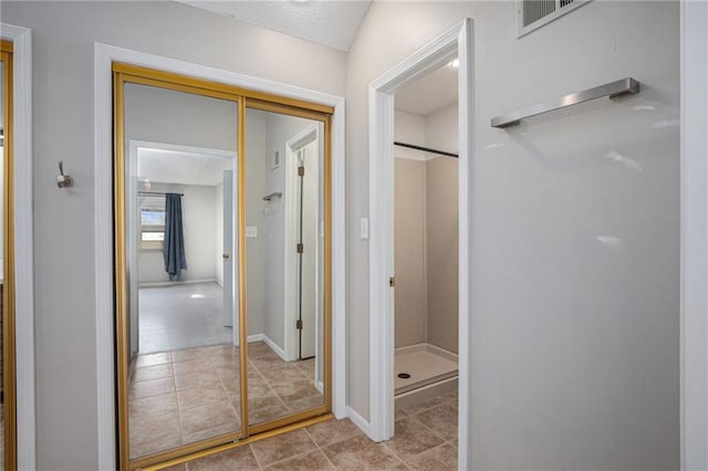 corridor featuring tile patterned flooring, visible vents, and baseboards