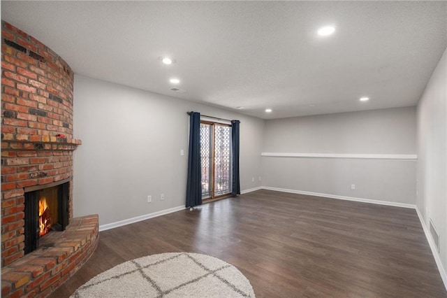 unfurnished living room with dark wood finished floors, a fireplace, baseboards, and recessed lighting